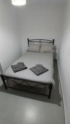 a bed with white sheets and towels on it at Harbor View Apartment Athens in Piraeus