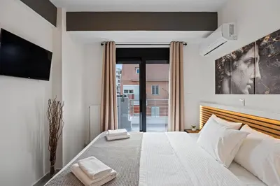 a bedroom with a large white bed and a tv at Athens Vein in Athens