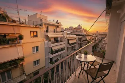 a balcony with a table and chairs and a sunset at Zwgrafou Deluxe For 4 Pers in Athens