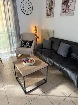 a living room with a black leather couch and a table at Bakopoulos resort στο Μπουρνάζι in Athens