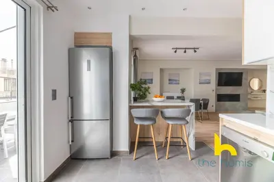 a kitchen with a stainless steel refrigerator and a table at Sunny Athenian Oasis Spacious Family Haven! in Athens