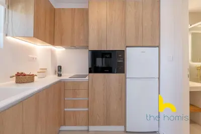 a kitchen with a white refrigerator and wooden cabinets at Eagle's Nest Athens Oasis with Culture & Views! in Athens