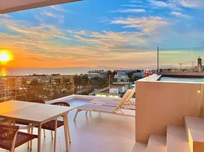 a balcony with a table and chairs and a sunset at Penthouse with private pool and unlimited Sea View in Glyfádas