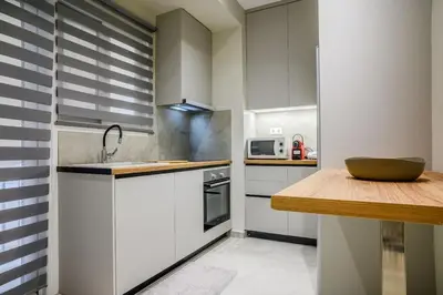 a kitchen with white cabinets and a wooden counter top at Central apartment in Piraeus in Piraeus