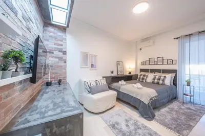 a bedroom with a bed and a chair and a brick wall at Cozy Seaside Apartment in Aphrodite Bay, Piraeus in Piraeus