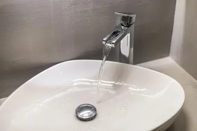 a white sink with water running from a faucet at Cozy Seaside Apartment in Aphrodite Bay, Piraeus in Piraeus