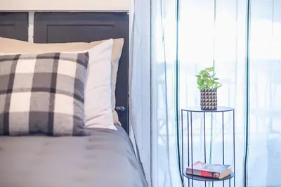 a bedroom with a bed and a window with a plant on a table at Cozy Seaside Apartment in Aphrodite Bay, Piraeus in Piraeus