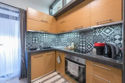 a kitchen with wooden cabinets and black and white tiles at Cozy Seaside Apartment in Aphrodite Bay, Piraeus in Piraeus
