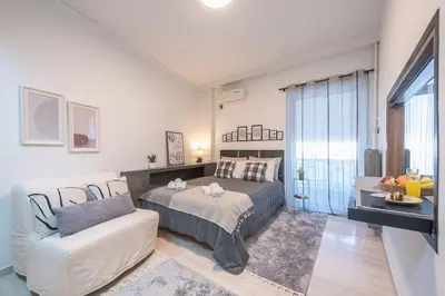 a bedroom with a bed and a couch and a window at Cozy Seaside Apartment in Aphrodite Bay, Piraeus in Piraeus