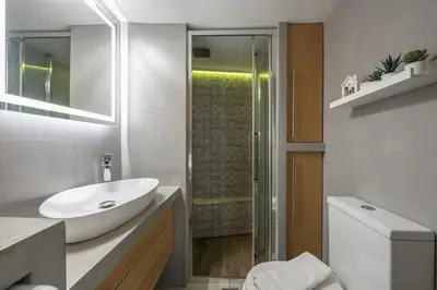 a white bathroom with a sink and a shower at Cozy Seaside Apartment in Aphrodite Bay, Piraeus in Piraeus