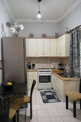 a kitchen with white cabinets and a table and a stove at Zografou Cozy Apartment in the heart of Athens! in Athens