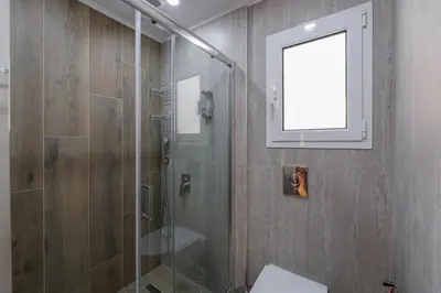 a bathroom with a shower with a glass door at Rhapsody in Blue Alimos Marina in Athens