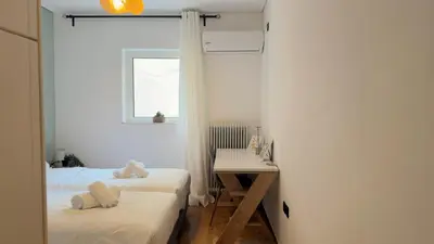 a bedroom with two beds and a desk and a window at The Stylish Central 2BR Residence for 5 in Athens