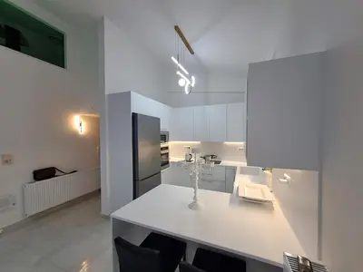 a kitchen with a white counter with chairs in it at Lula Urban Apartment in Athens