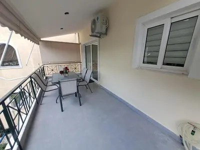a balcony with a table and chairs and a clock at Lula Urban Apartment in Athens