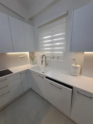 a white kitchen with white cabinets and a sink at Lula Urban Apartment in Athens