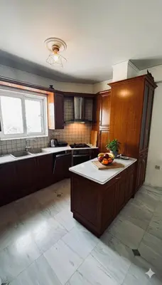 a kitchen with wooden cabinets and a bowl of fruit on a counter at The Lotus House - Premium Coastal Living in Porto Rafti