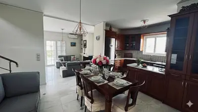 a kitchen and living room with a table with flowers on it at The Lotus House - Premium Coastal Living in Porto Rafti