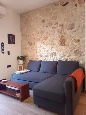 a blue couch in a living room with a stone wall at The Fisherman's Romance in Piraeus