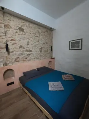 a bedroom with a blue bed with a stone wall at The Fisherman's Romance in Piraeus