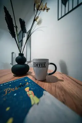 a coffee cup sitting on a wooden table with a book at Noir & Blanc in the Heart of Nea Smyrni in Athens