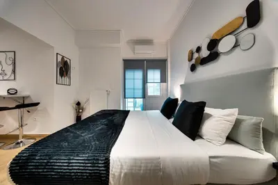 a bedroom with a large white bed and a couch at Noir & Blanc in the Heart of Nea Smyrni in Athens