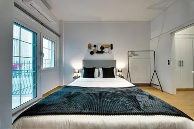 a bedroom with a large bed in a room with windows at Noir & Blanc in the Heart of Nea Smyrni in Athens