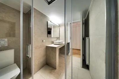 a bathroom with a sink and a glass shower door at Noir & Blanc in the Heart of Nea Smyrni in Athens