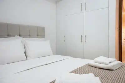 a white bedroom with a bed with white pillows at Elysian Lycabettus-Resilience in Athens
