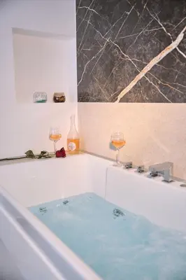 a bath tub with two glasses of wine in it at SOLUNA Hideaway Athens - Luxury Jacuzzi Suite in Athens