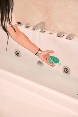 a woman in a bath tub holding a scrubber at SOLUNA Hideaway Athens - Luxury Jacuzzi Suite in Athens
