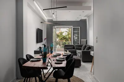 a living room with a wooden table and black chairs at Eclipse Asklipion Voula in Athens