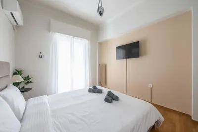 a bedroom with a white bed with a television on the wall at Athena House Elegant Stay For Families By Greece Apartments in Athens