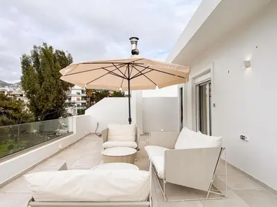 a balcony with white furniture and an umbrella at Sunlit Retreat in Voula Center in Athens
