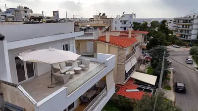 a balcony with an umbrella and chairs on a building at Sunlit Retreat in Voula Center in Athens