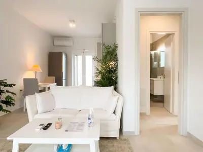a living room with a white couch and a table at Sunlit Retreat in Voula Center in Athens