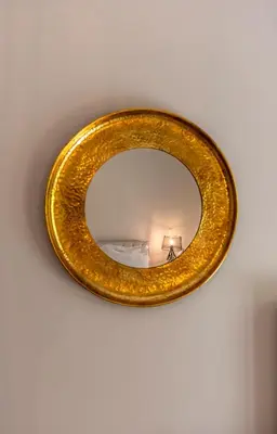 a gold circular mirror hanging on a wall at 2b apartment beyond a house Glyfada center in Athens