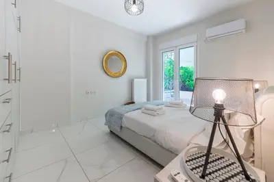 a white bedroom with a bed and a mirror at 2b apartment beyond a house Glyfada center in Athens
