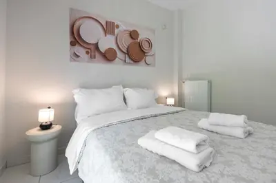 a white bedroom with a large bed with towels on it at 2b apartment beyond a house Glyfada center in Athens
