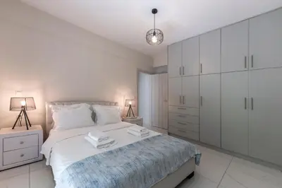 a white bedroom with a large bed and white cabinets at 2b apartment beyond a house Glyfada center in Athens