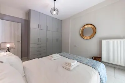 a white bedroom with a bed and a mirror at 2b apartment beyond a house Glyfada center in Athens
