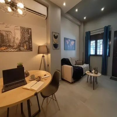 a living room with a table with a laptop on it at Cozy Split-Level Loft by Piraeus Port in Piraeus
