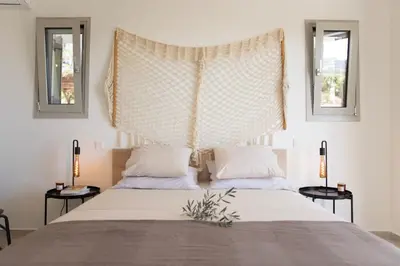a bedroom with a large bed with two windows at Athens Riviera Villa overlooking the Aegean sea in Anavissos