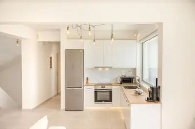 a kitchen with white cabinets and a stainless steel refrigerator at Athens Riviera Villa overlooking the Aegean sea in Anavissos