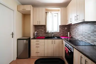 a kitchen with wooden cabinets and a black refrigerator at Cozy loft in the western suburbs of Athens! in Athens