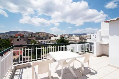 a white table and chairs on a balcony with a view at Cozy loft in the western suburbs of Athens! in Athens