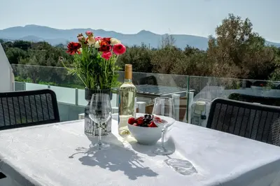 a table with a bottle of wine and a vase of flowers at Villa Oneiron in Anavissos