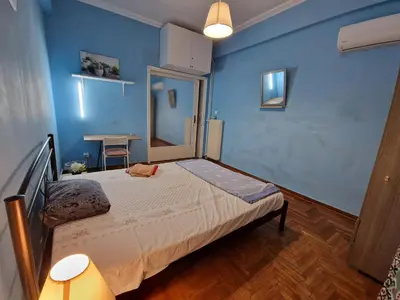 a bedroom with a bed with a blue wall at Cosy executive room in beautiful n quiet flat in Athens