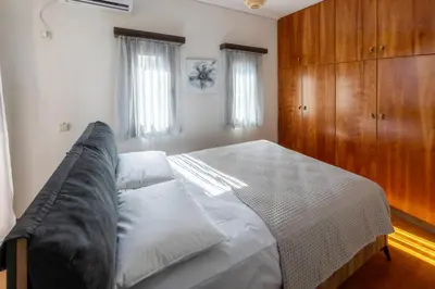 a bedroom with a bed and a wooden cabinet at Villa Elysia in Porto Rafti