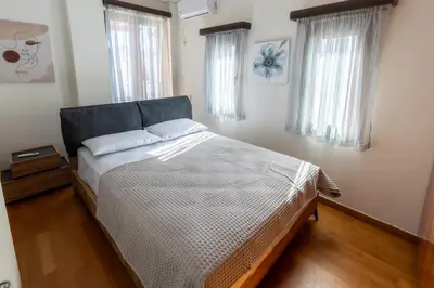 a bedroom with a bed with a blue headboard and two windows at Villa Elysia in Porto Rafti